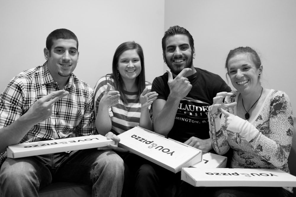Group of friends holding &pizza boxes, showing why &pizza delivery hits different with bold flavors and quality.