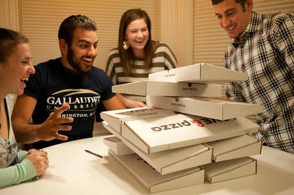 Friends using &pizza boxes during a late night pizza hangout.
